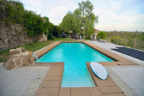 The pool terrace with a surfboard resting on the steps, looking out over the hills at dusk