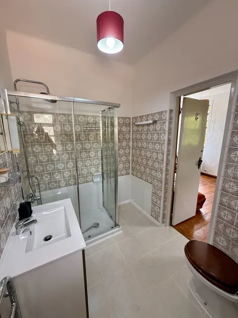 A second bathroom with patterned tile, shower and toilet