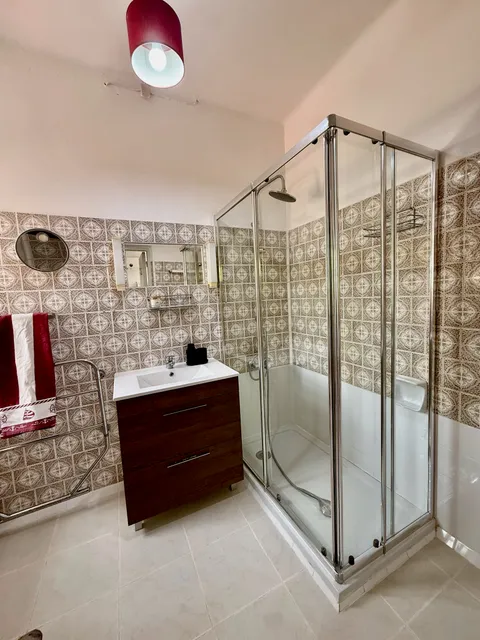 Bathroom with patterned tile, a glass shower enclosure and vanity